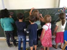 Kinder üben das Zahlenschreiben an der Tafel